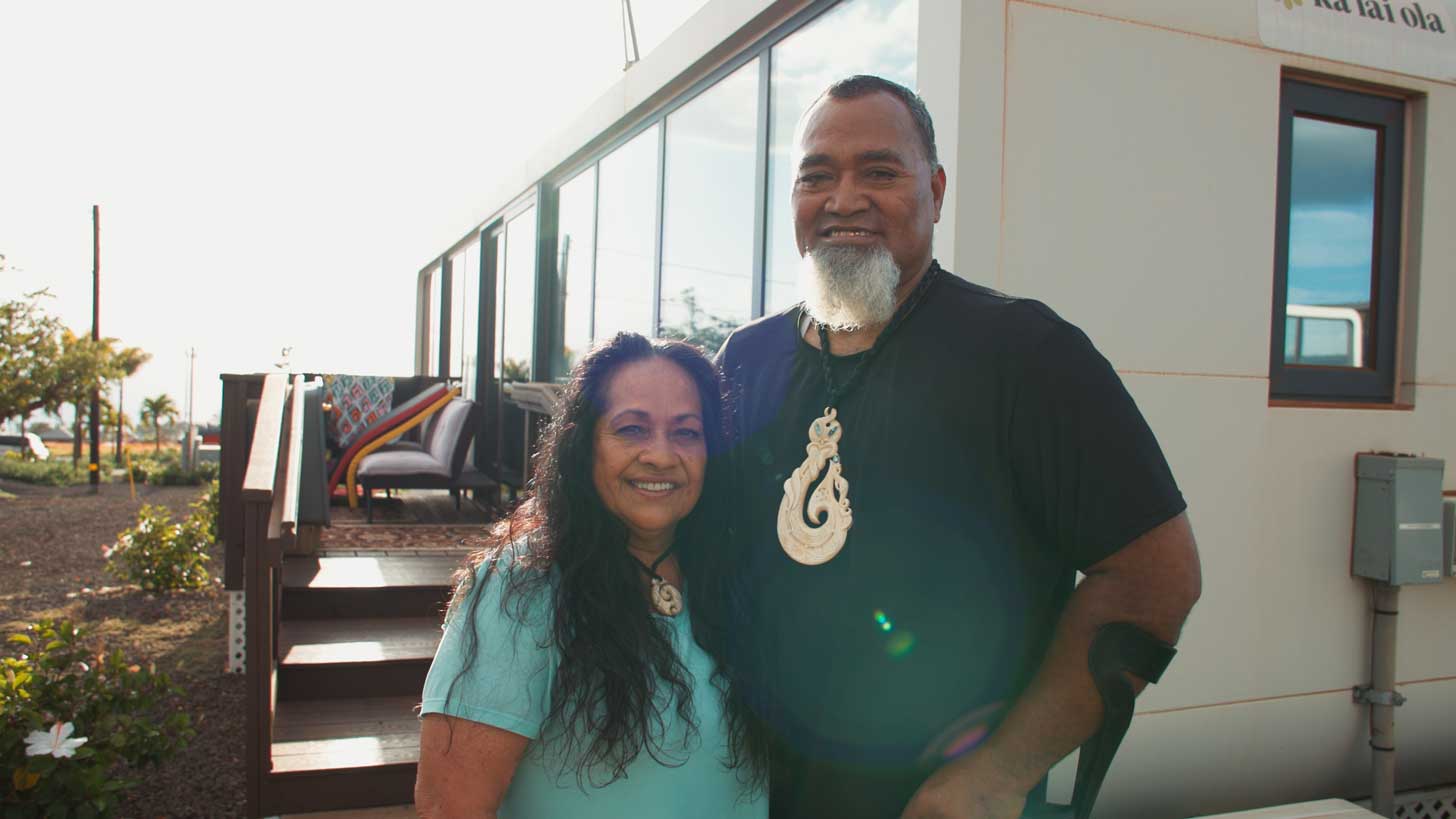 A Polynesian couple outside of their tiny home in Hawaii
