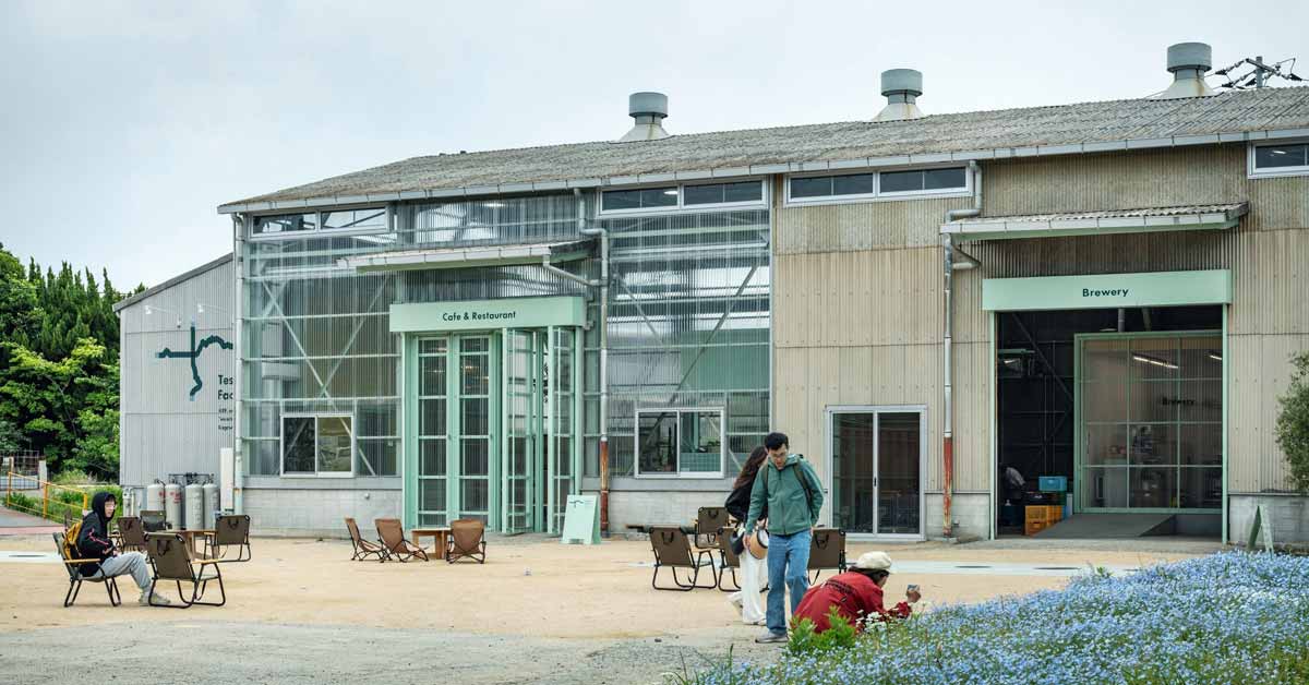 People mill about the exterior of a factory turned cafe on Teshima Island in Japan