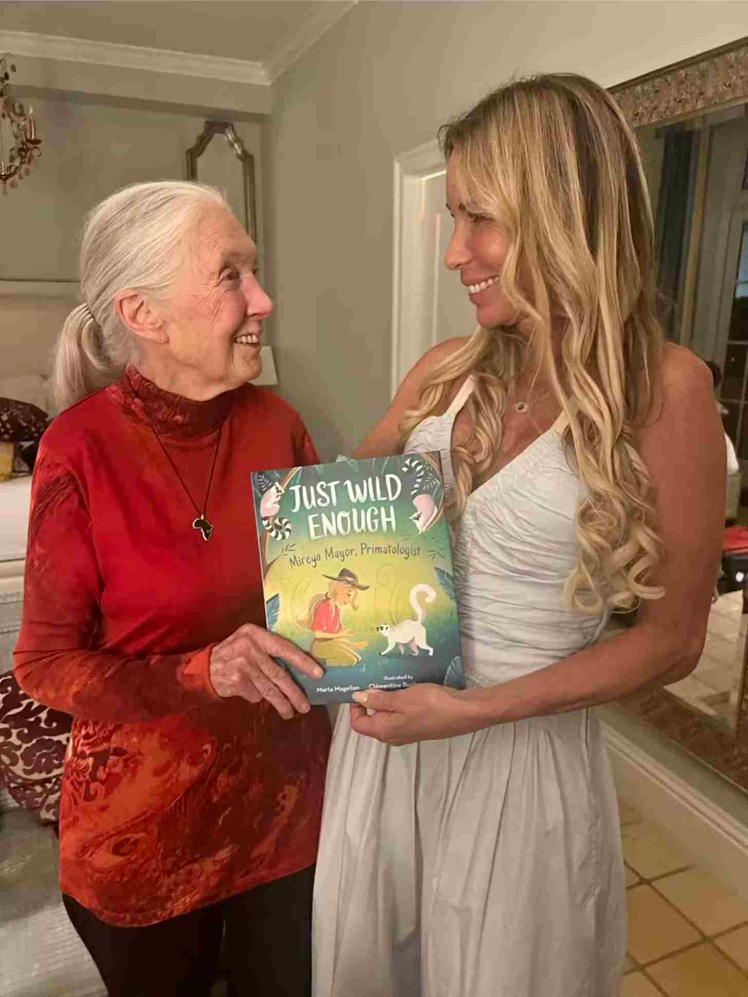 Two women face each other, smiling and holding a book