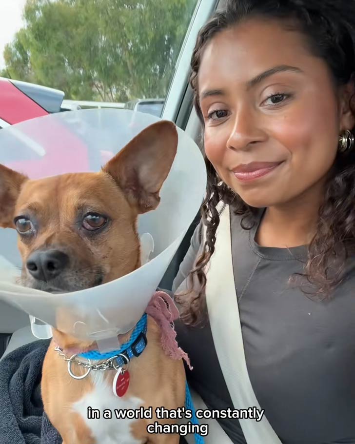 A woman with tan skin and dark curly hair takes a selfie with a Chihuahua