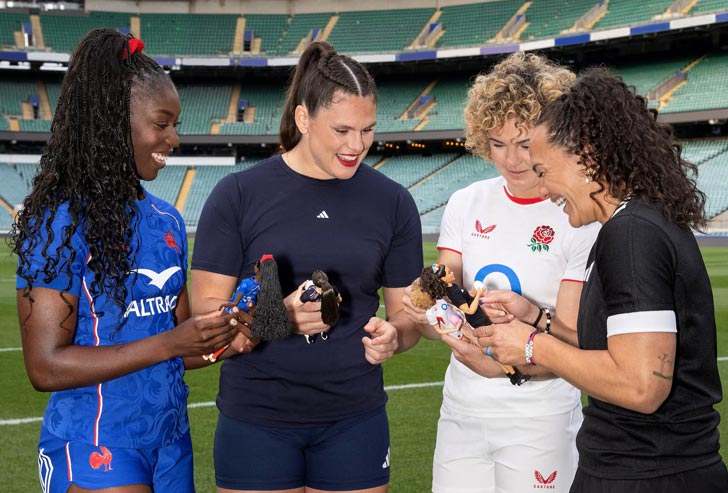 Four women rugby players hold Barbie dolls that look like them
