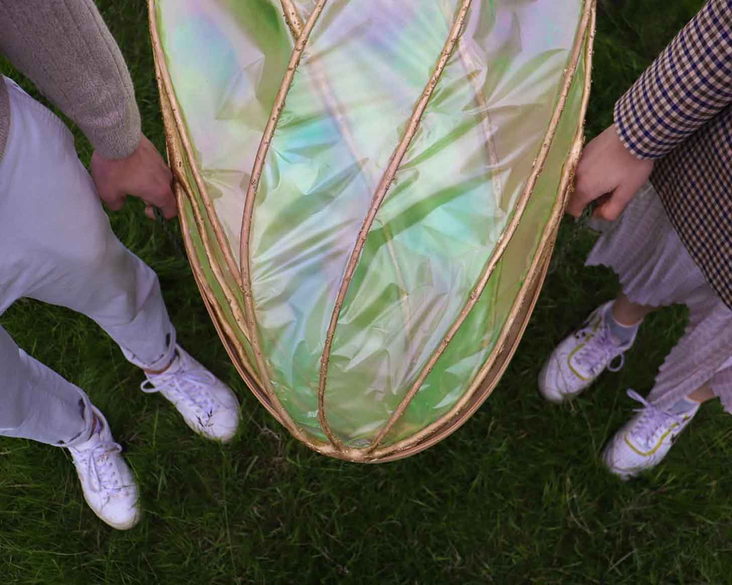 Two hands hold onto a coffin covered in transparent seaweed wings