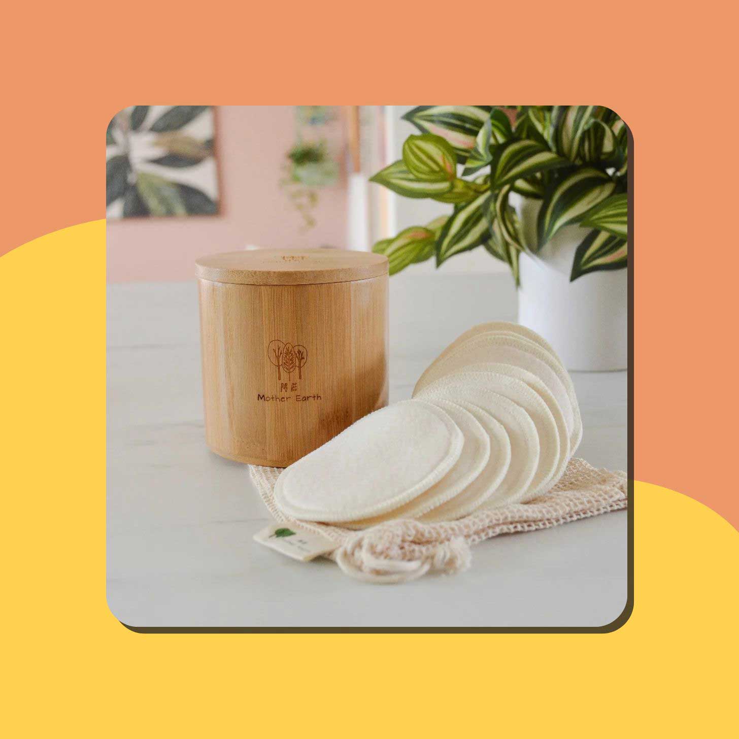 A set of cotton rounds sits next to a bamboo storage container on a bathroom counter