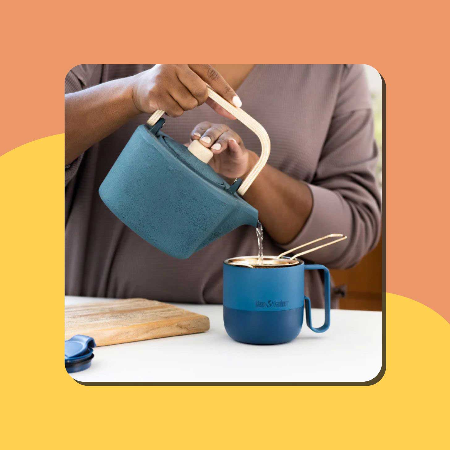 A person pours water into a blue Klean Kanteen mug