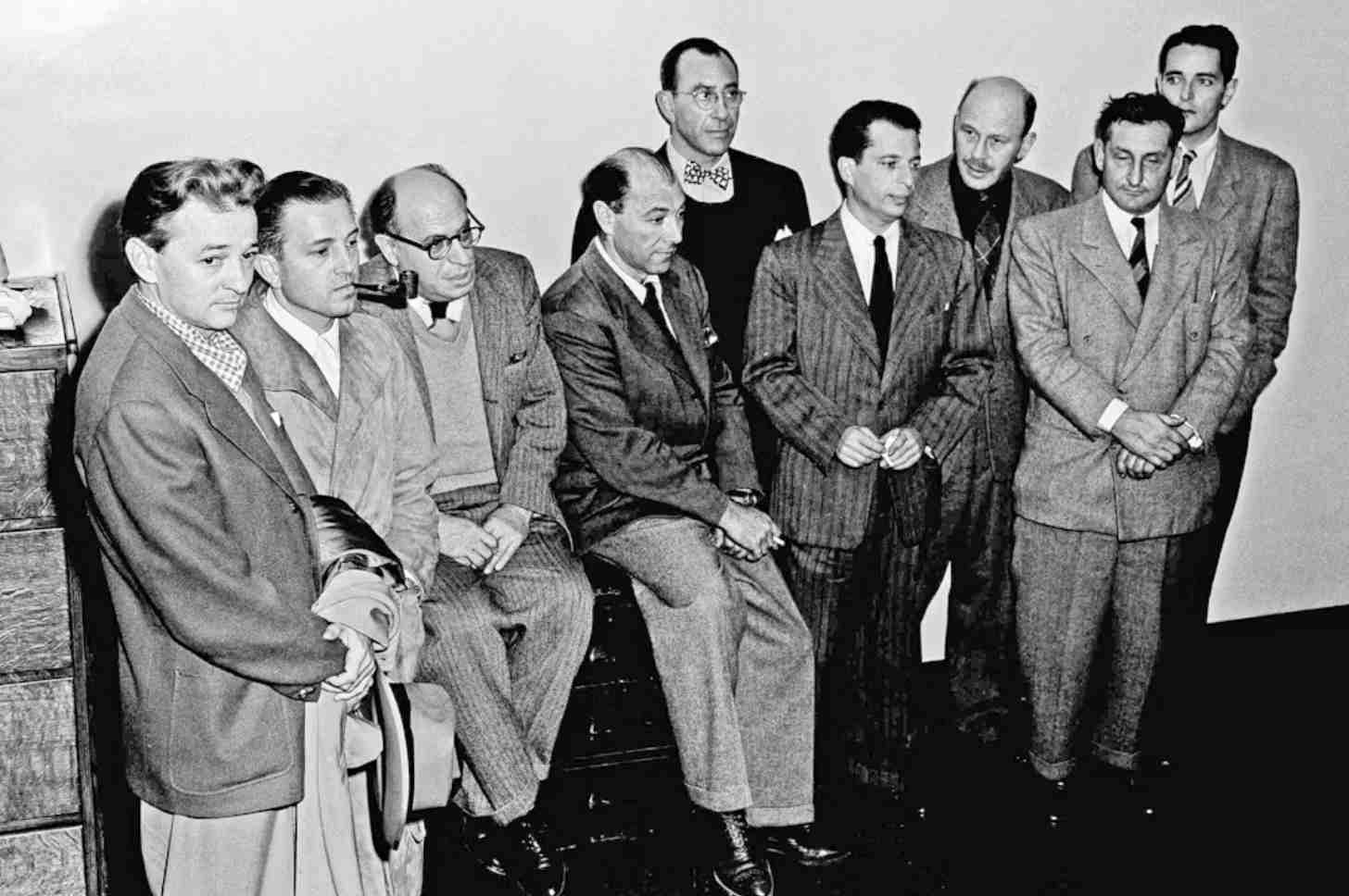 Ten men in suits stand together in a black-and-white photograph taken in the mid-20th century.