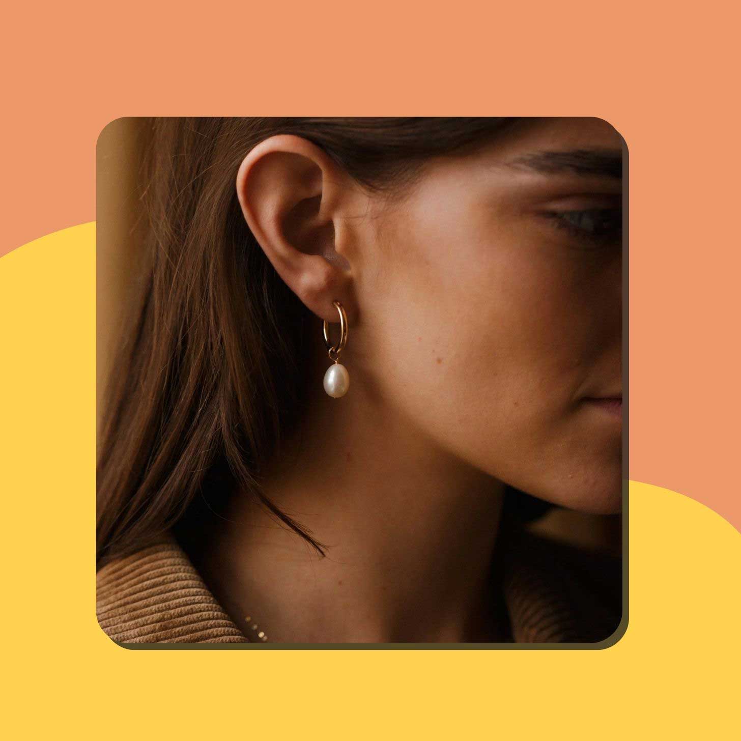 A close-up of a pearl earring on a woman's ear