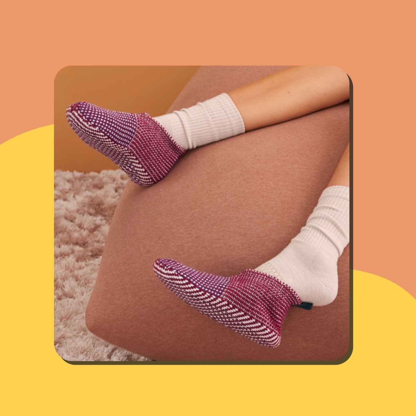 A person wears a pair of pink slippers with white socks