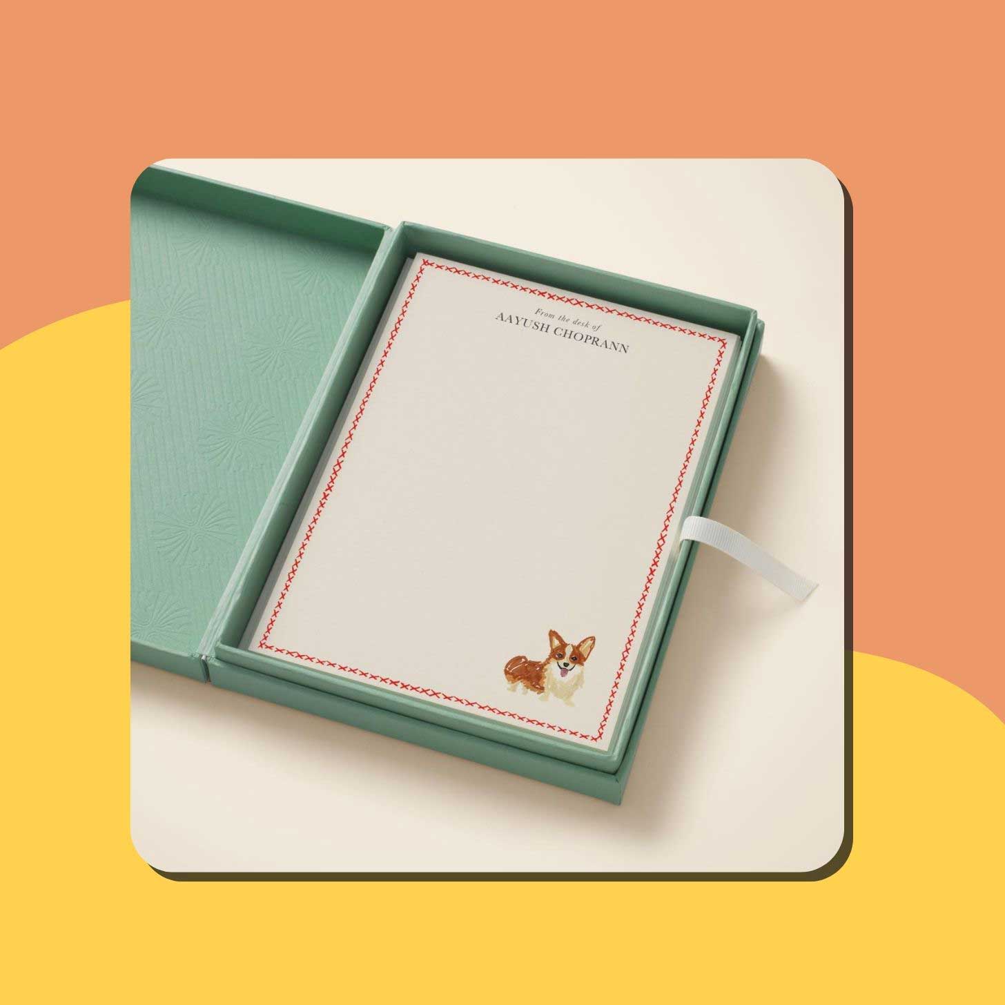 A set of custom stationery with a red border and a tan corgi at the bottom right