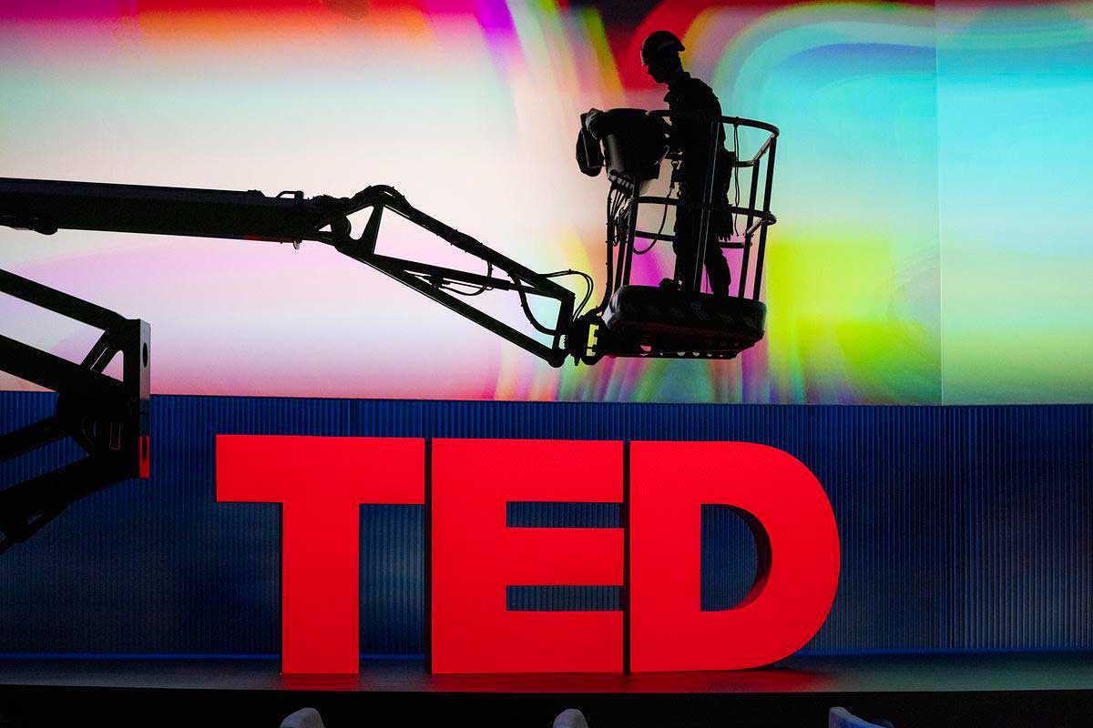 A stage manager assembles red TED letters on a stage