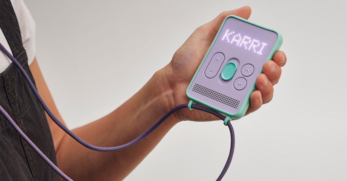 A kid holds up a small purple square-shaped device that reads KARRI in LED dots