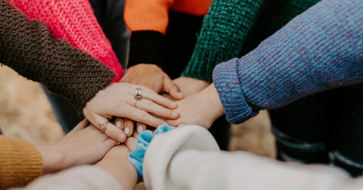Hands of multiple people laid down in the middle a circle