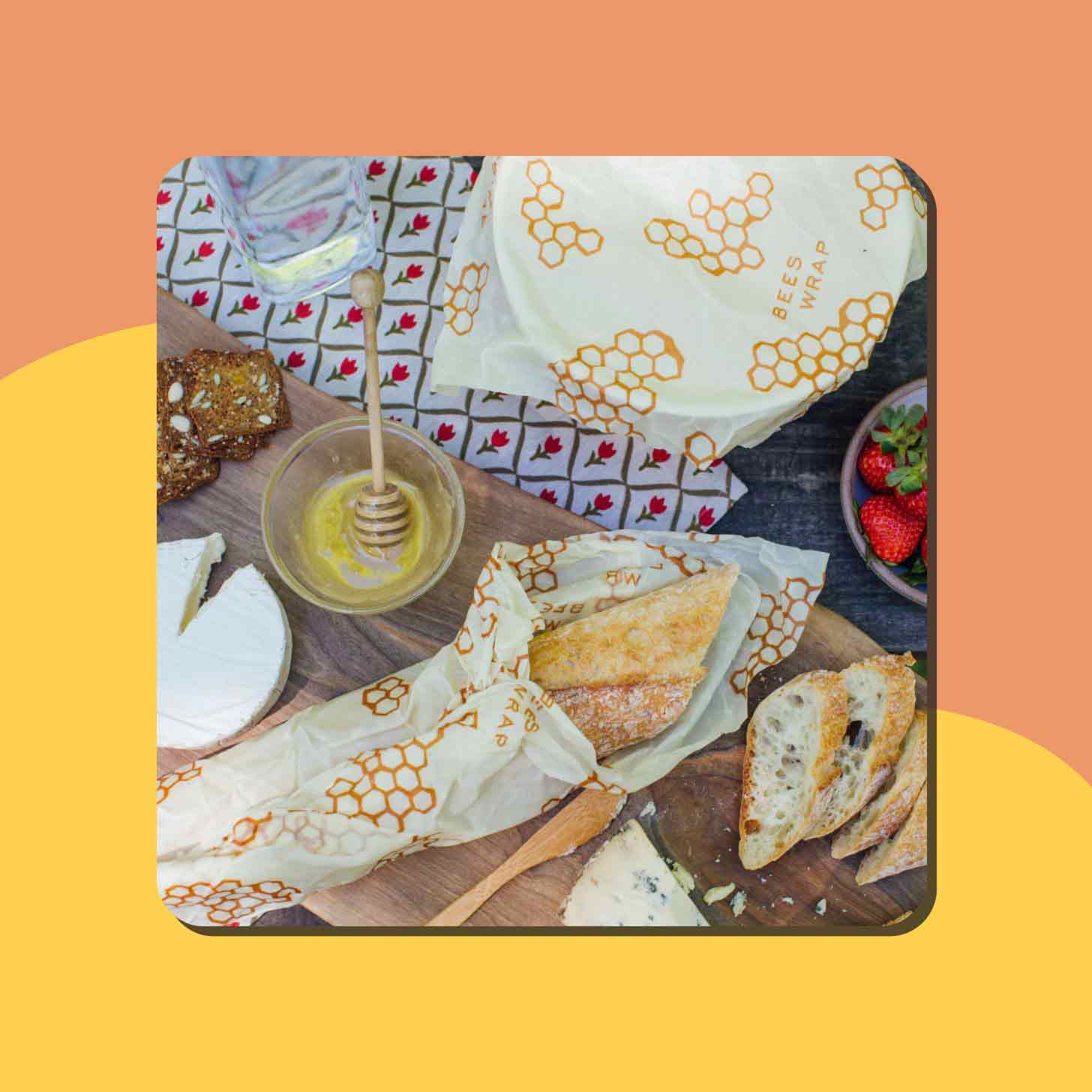 A picnic setting with breads, honeys, and fruits, with some items wrapped in Bee's Wrap