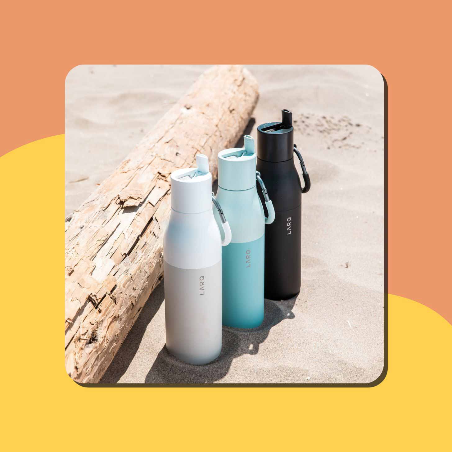 Three water bottles from LARQ sit in the sand
