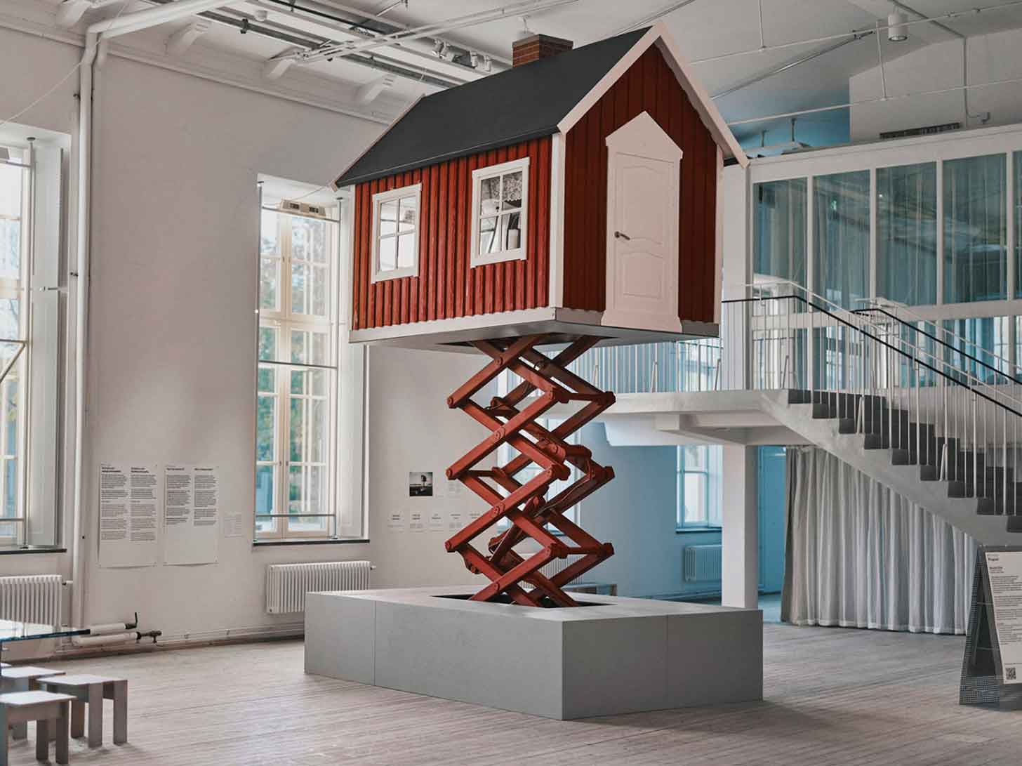 A red cottage on a scissor lift
