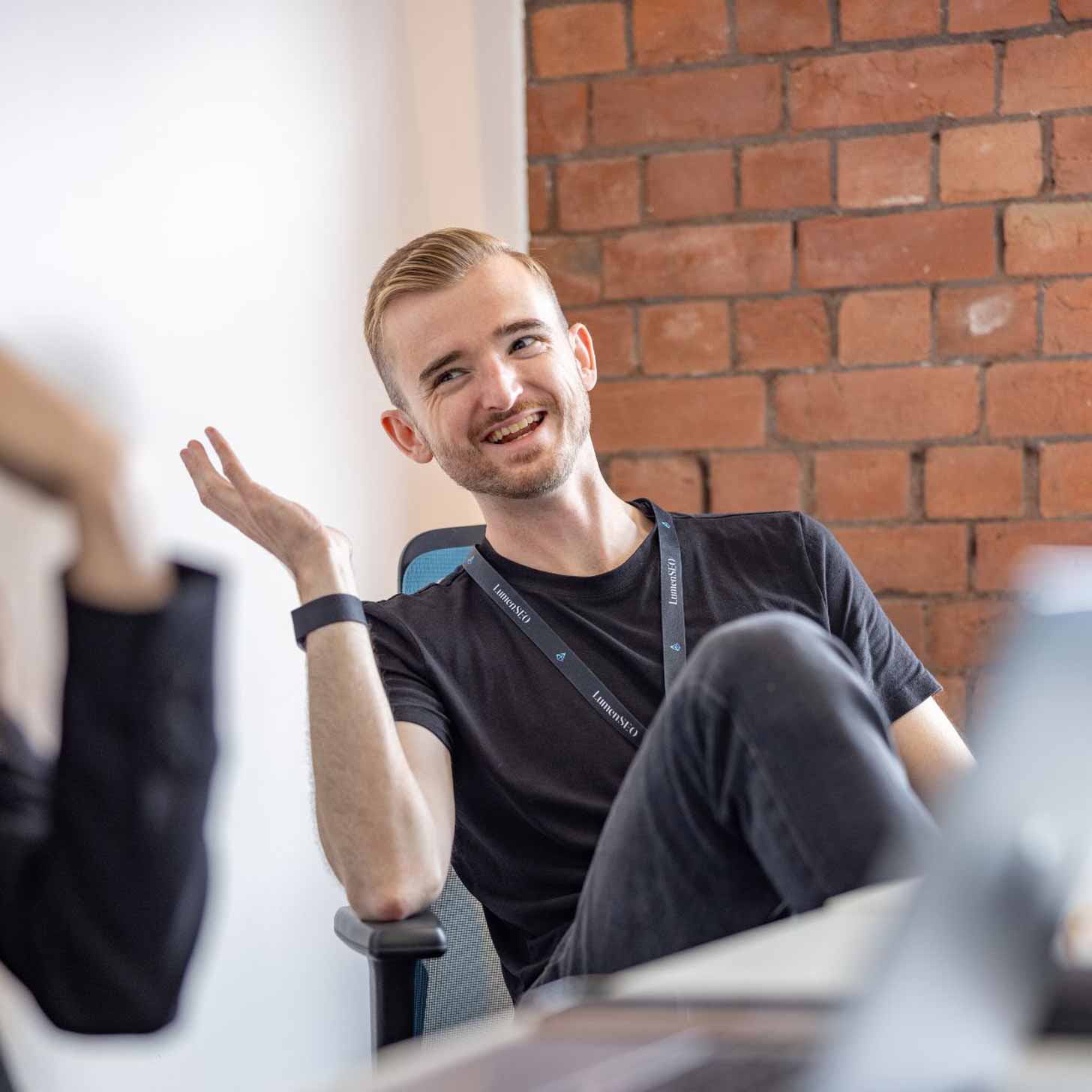 A young CEO with blond hair wears a black t-shirt and lanyard