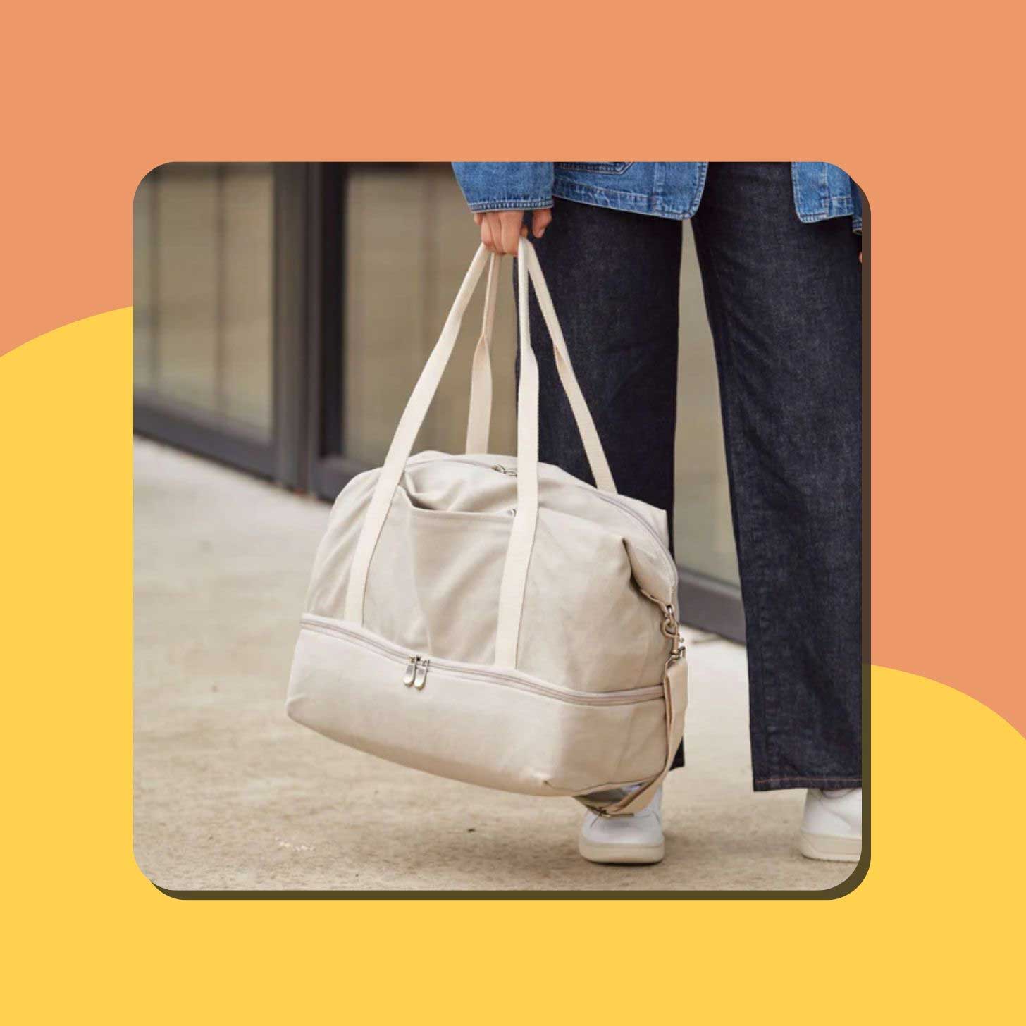 A person holds a white canvas weekender bag from Lo and Sons