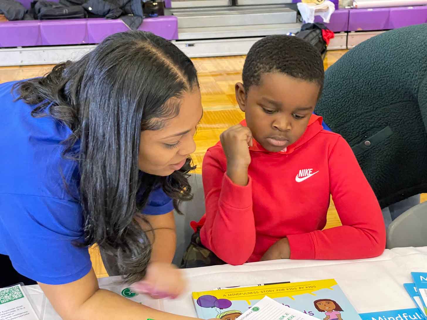 A Black child reads a mindfulness book with a Black teacher in Atlanta Public Schools.