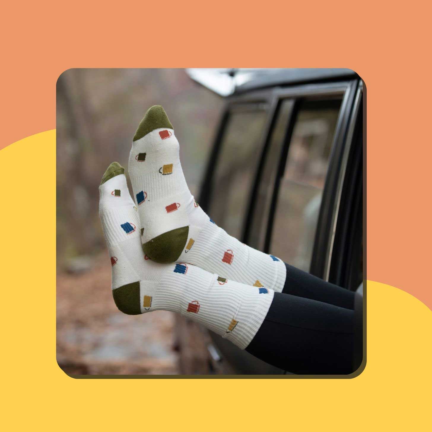 Feet sticking out of a car window, wearing white socks with mugs on them