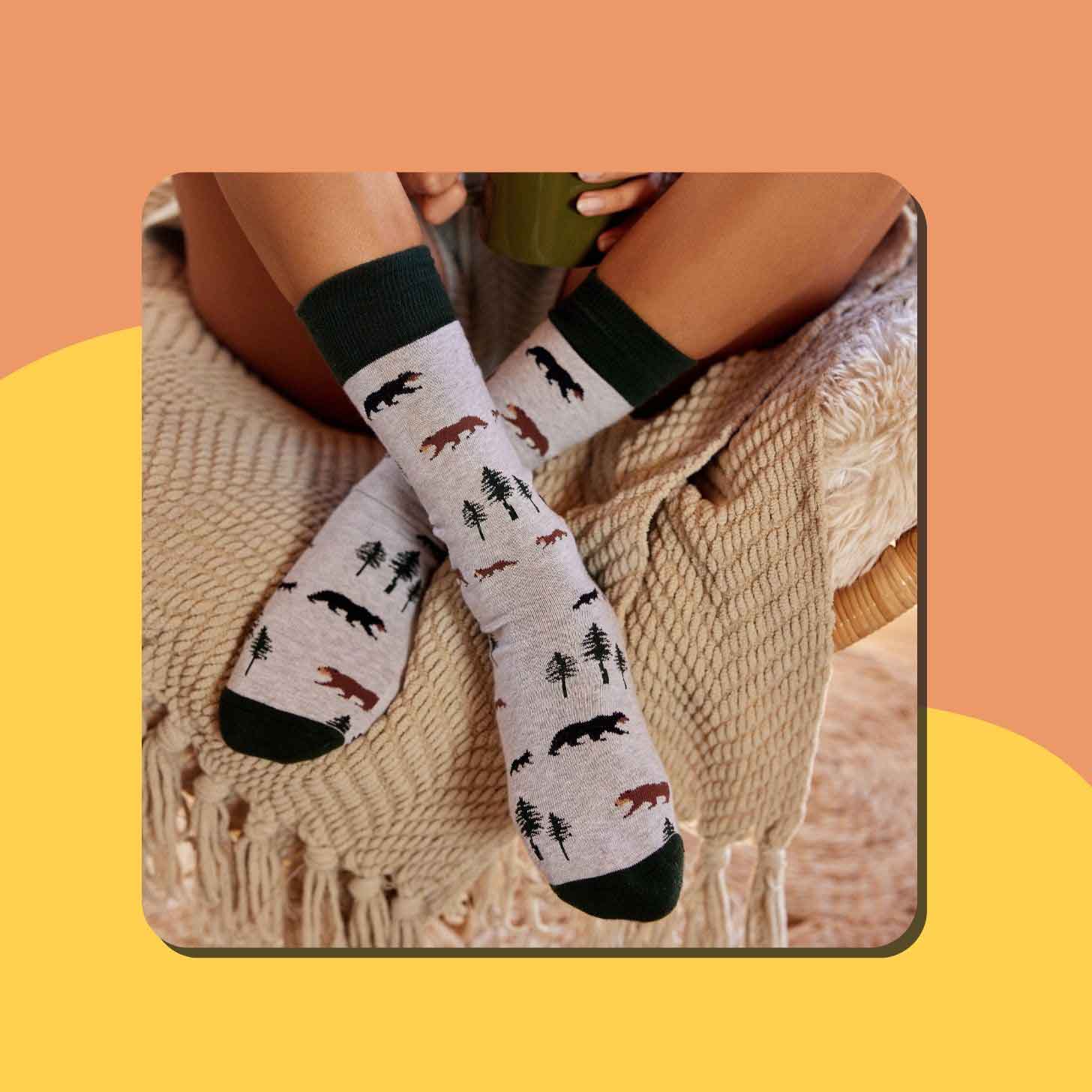 A close-up of a person wearing gray socks with bears and trees on them
