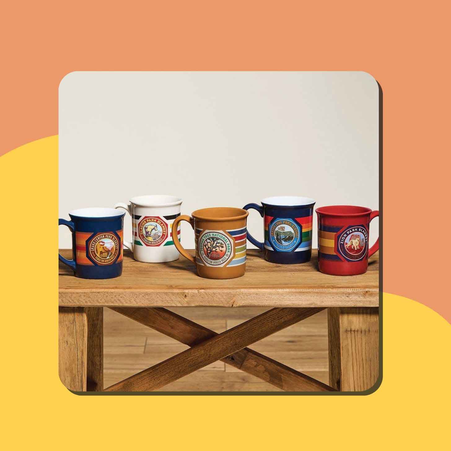 A series of five colorful national park mugs on a table