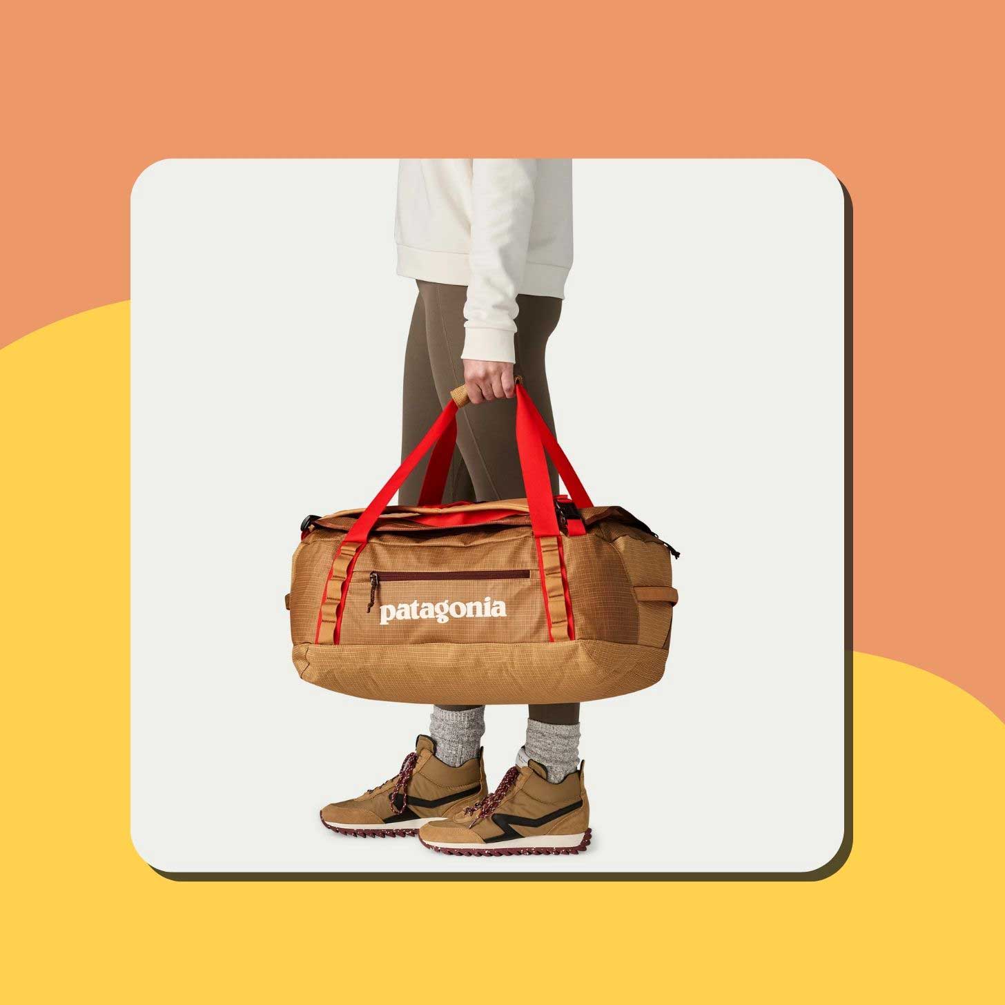 A person holds a khaki Patagonia duffle bag at their side, with red straps