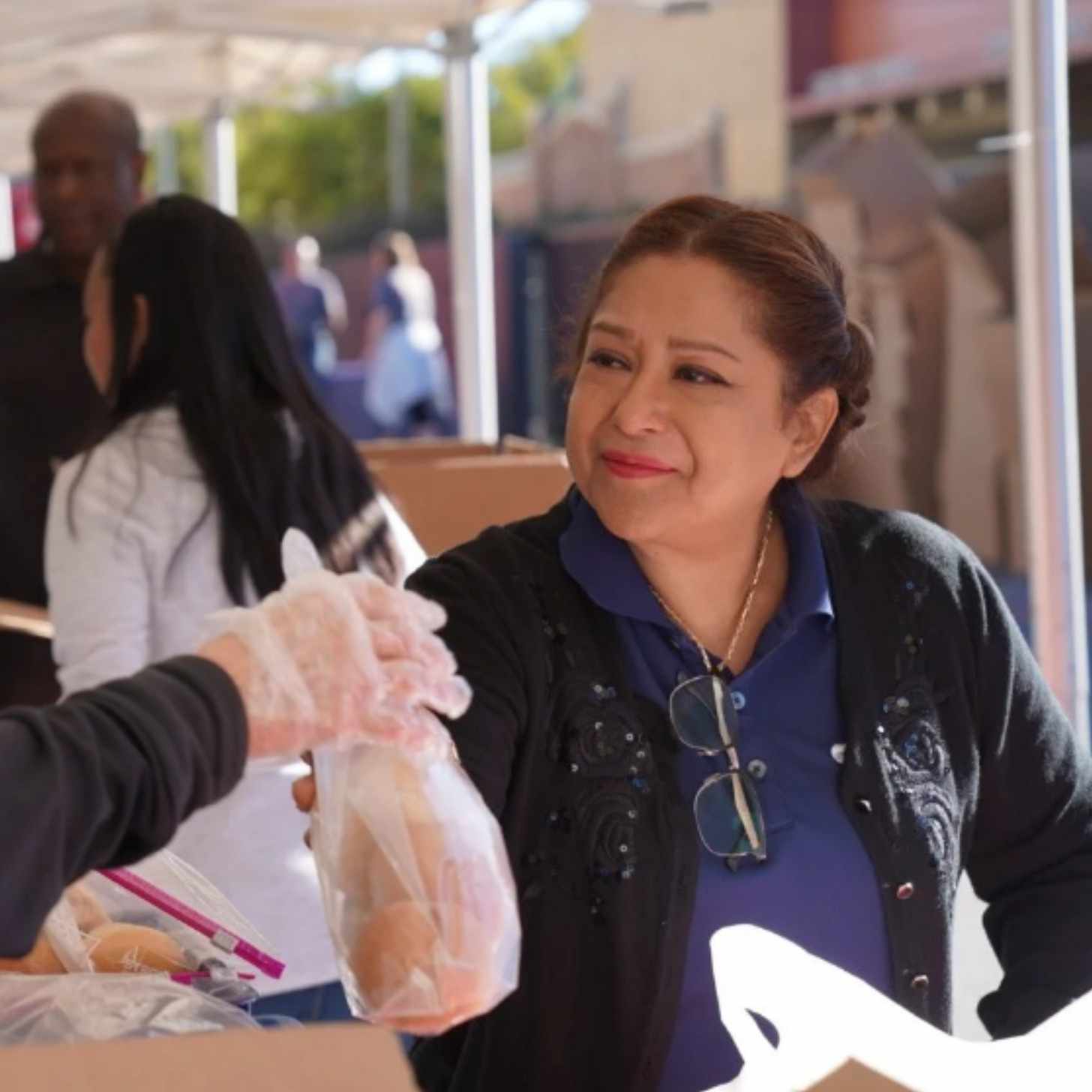 A woman smiles as she's handed a bag at a food bank line