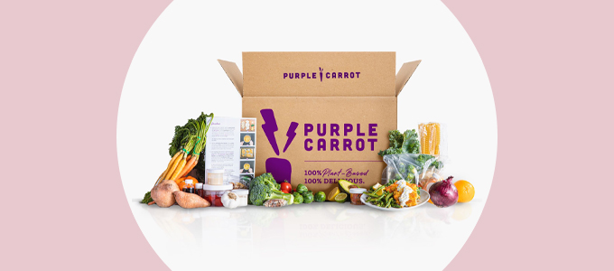 A brown shipping box with the purple "Purple Carrot" logo on the side of it surrounded by colorful fruits and vegetables..