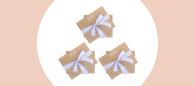 3 matching brown boxes with light purple bows wrapped around each of them.