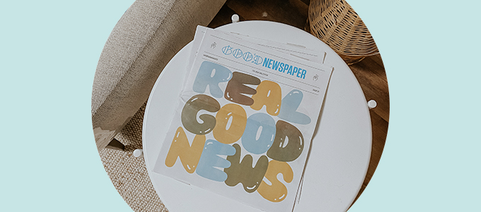 Overhead image of a Goodnewspaper sitting on a side table. The cover reads "Real Good News."