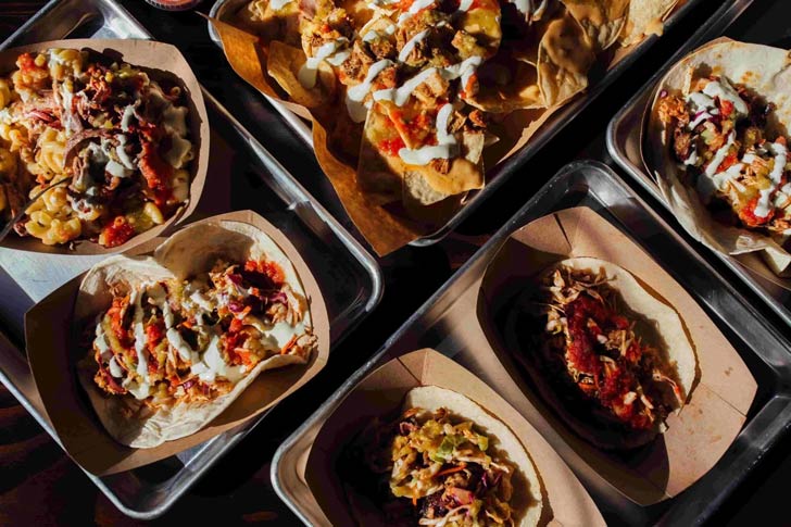 A flat-lay of food from Muchachos: Street tacos, nachos, and hatch mac n cheese