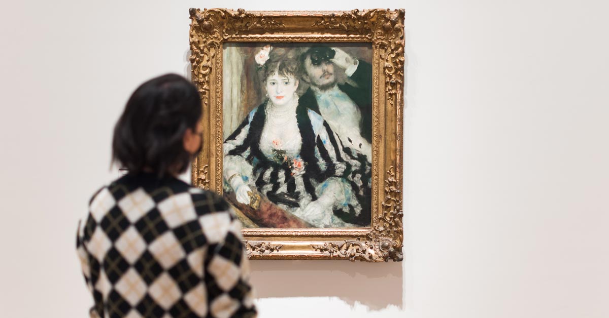 A woman looks at Pierre-Auguste Renoir, (1841- 1919) La Loge, 1874 at The Courtauld Gallery in London