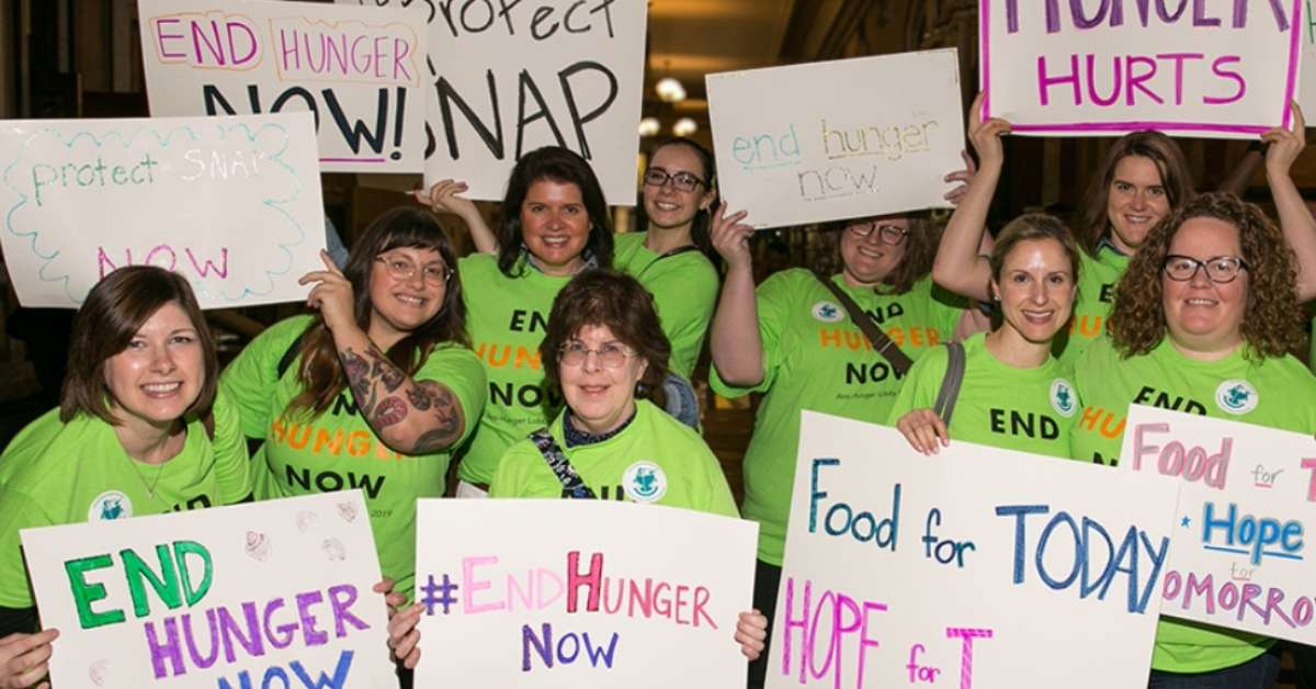 A group of women in green protest for hunger rights. Various signs read: Protect Snap, and End hunger!