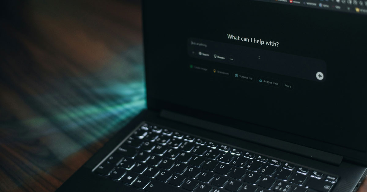 A laptop screen displays ChatGPT, asking "how can I help?"