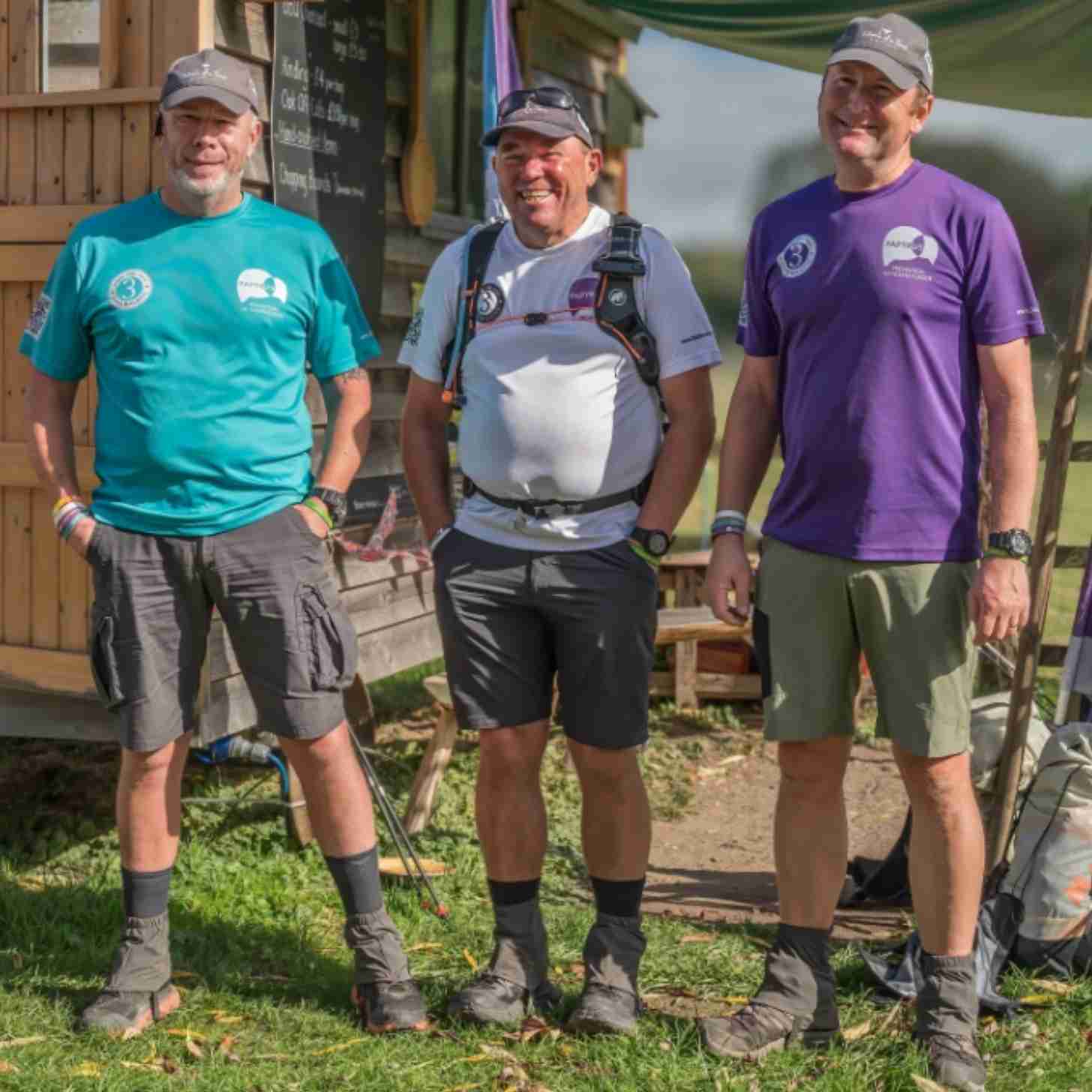 Three dads smile as they look towards a camera. They are dressed for the trailhead.