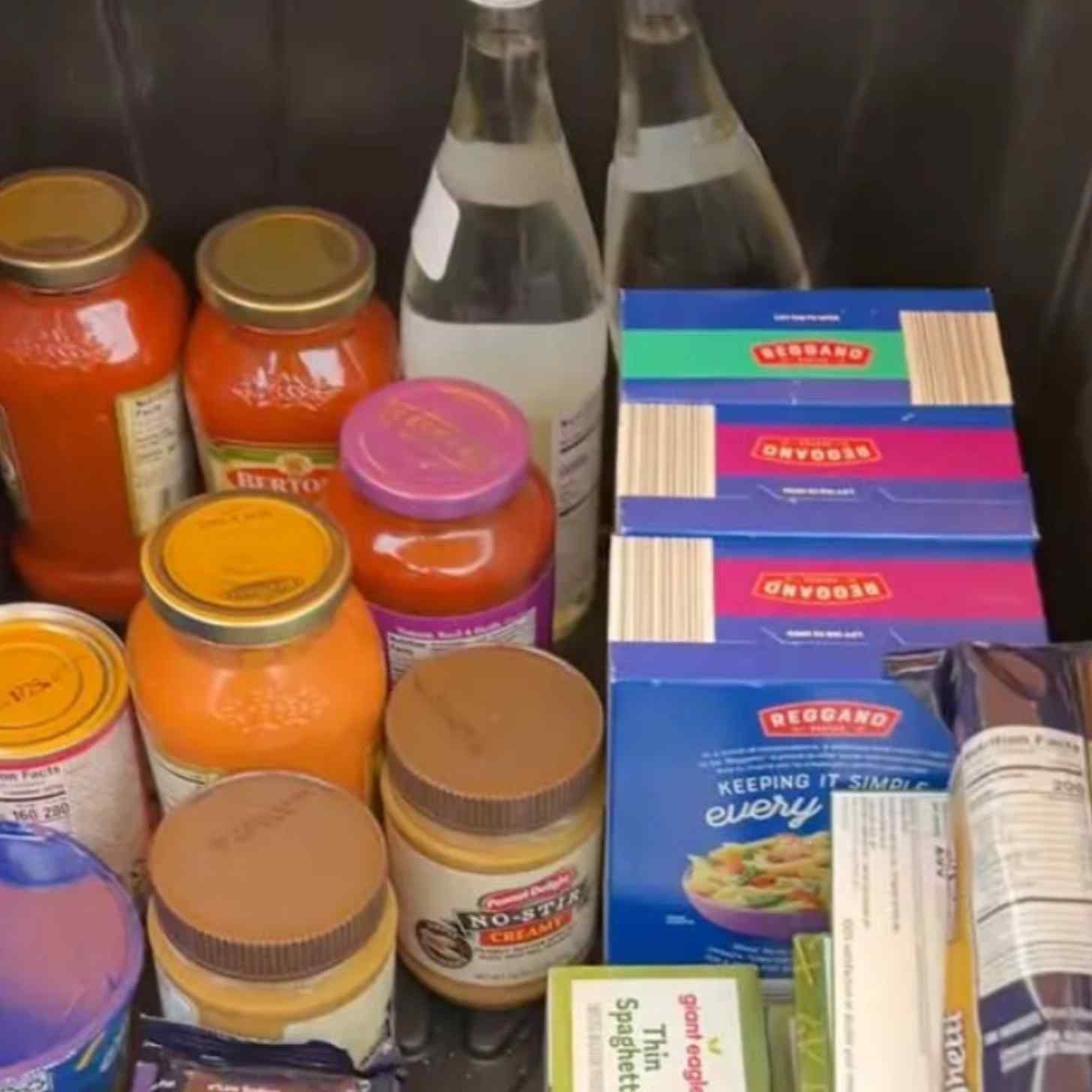 A kitchen counter filled with cans, bottles, and pasta boxes