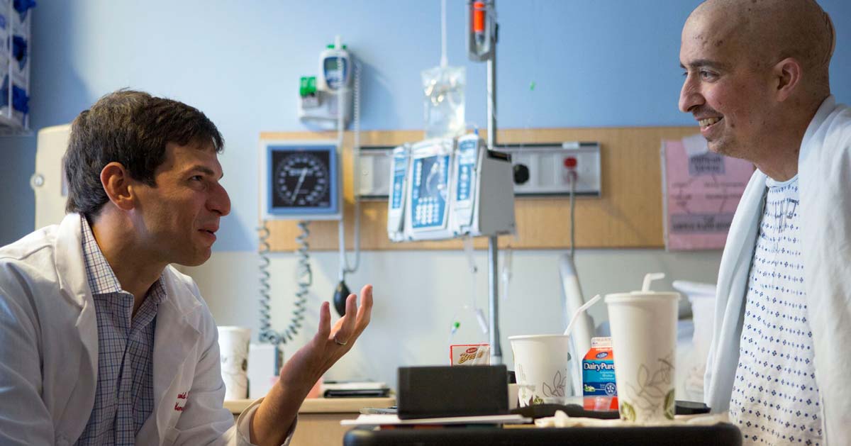 Dr. David Fajgenbaum speaks to a patient in a hospital