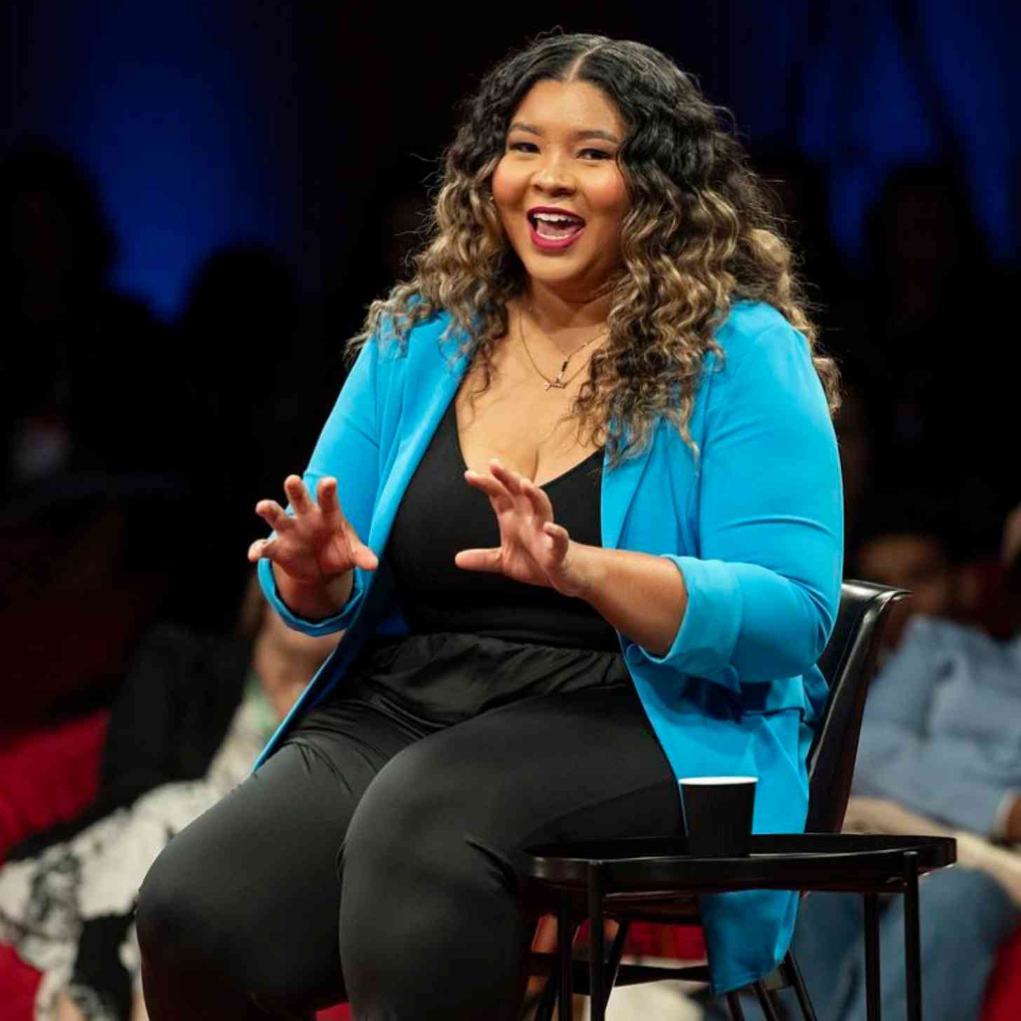 A woman smiles as she talks from a conference stage