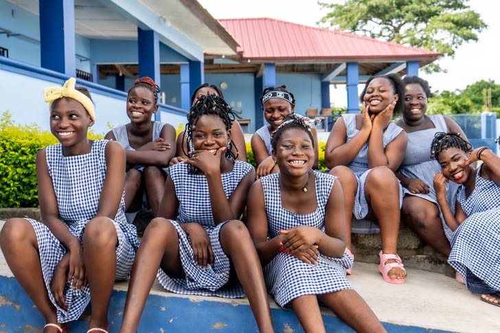 A group of girls in Ghana smiles in matching dresses