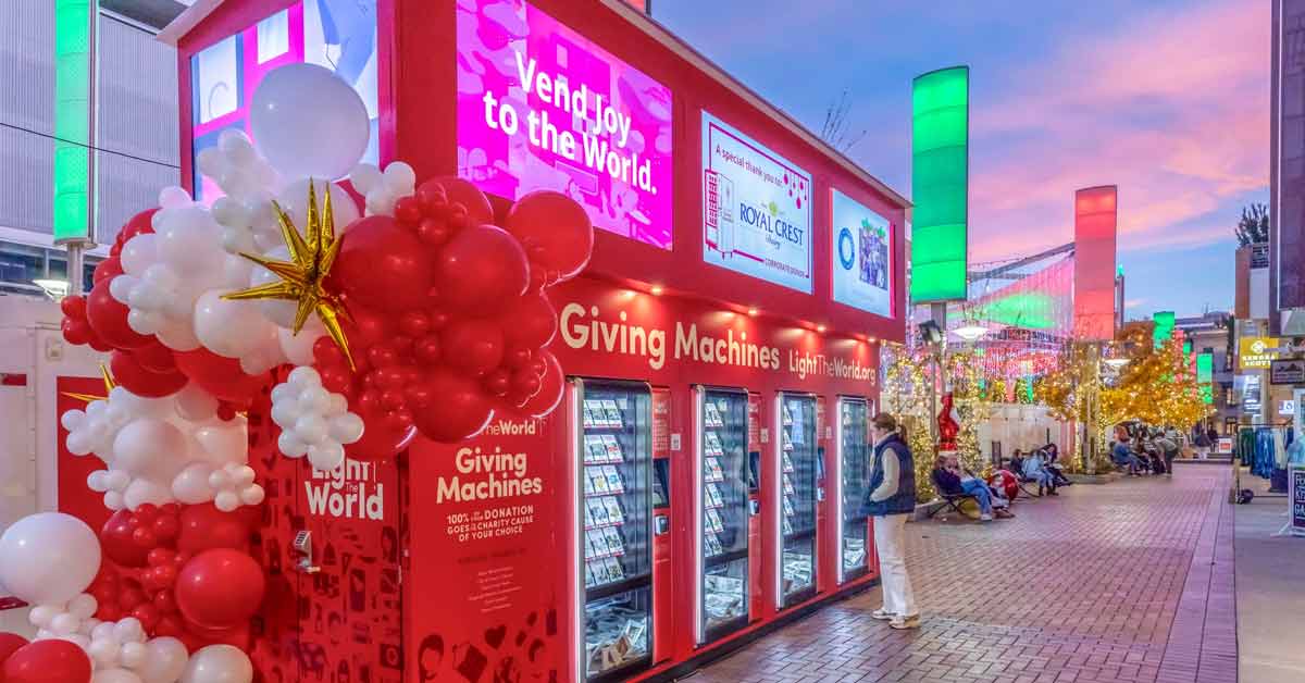 A person stands in front of a Light the World Giving Machine in Denver