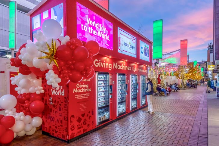 A person stands in front of a Light the World Giving Machine in Denver