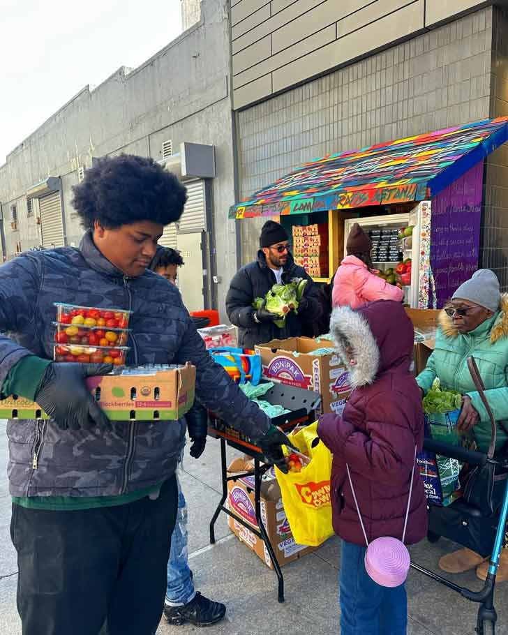 A teen boy distributes free food to community members in Harlem, NY
