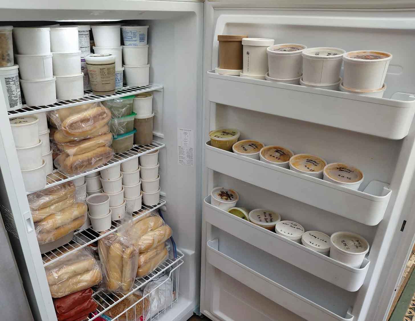 A fridge filled to the brim with takeout containers of soup
