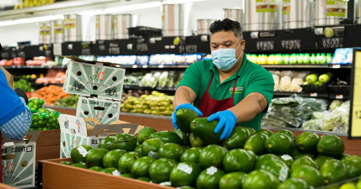 A worker at Compare Foods stocks produce in a grocery store