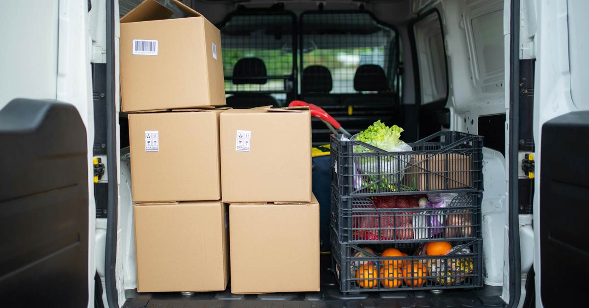Boxes of groceries stacked in the trunk of a delivery van