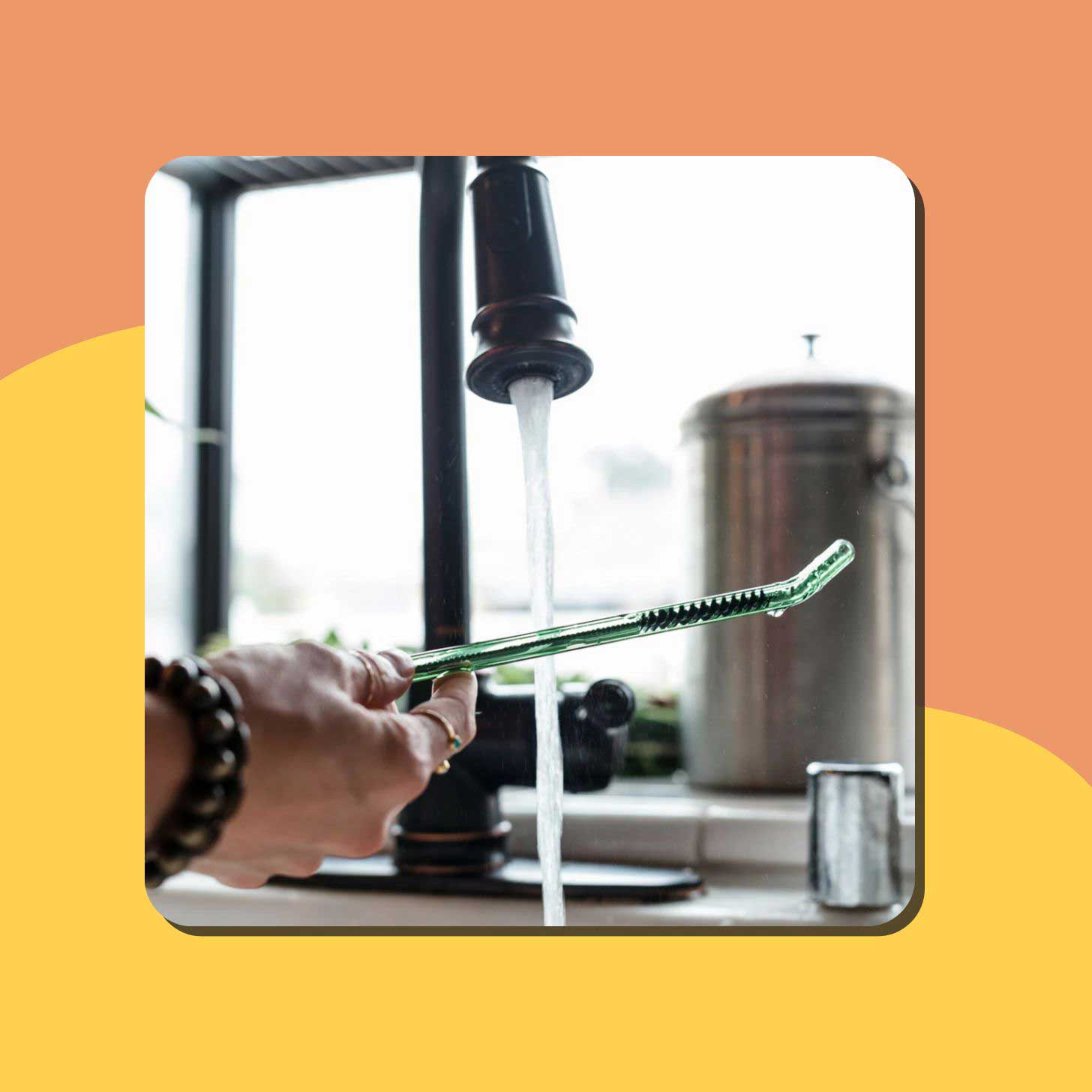 A green glass straw is run under water