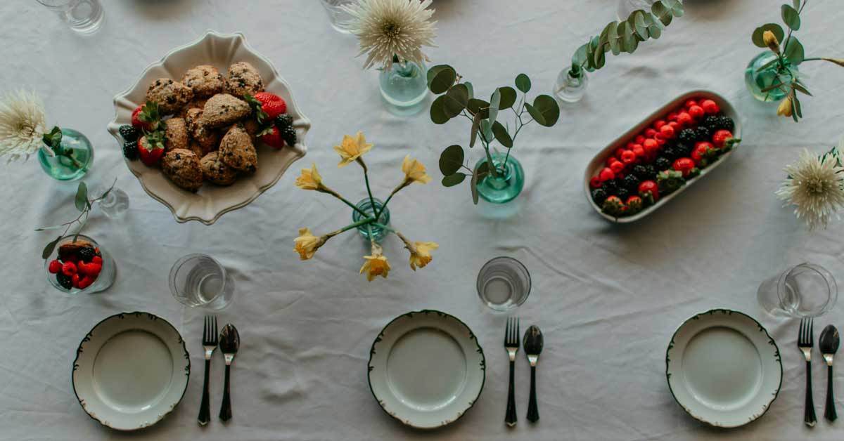 A table is made up with food, plates, and flowers
