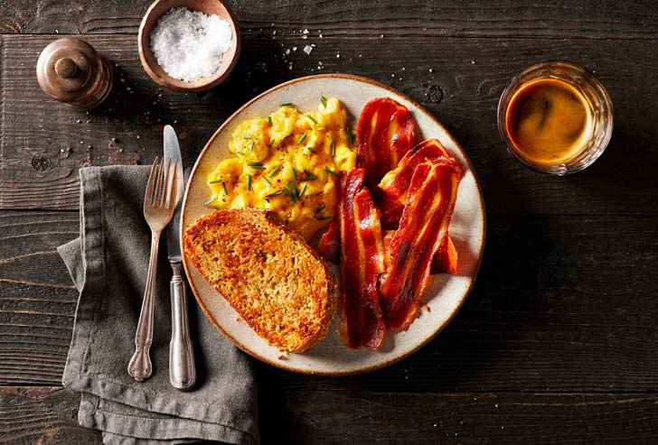 A plate of eggs, bacon, and toast on a table