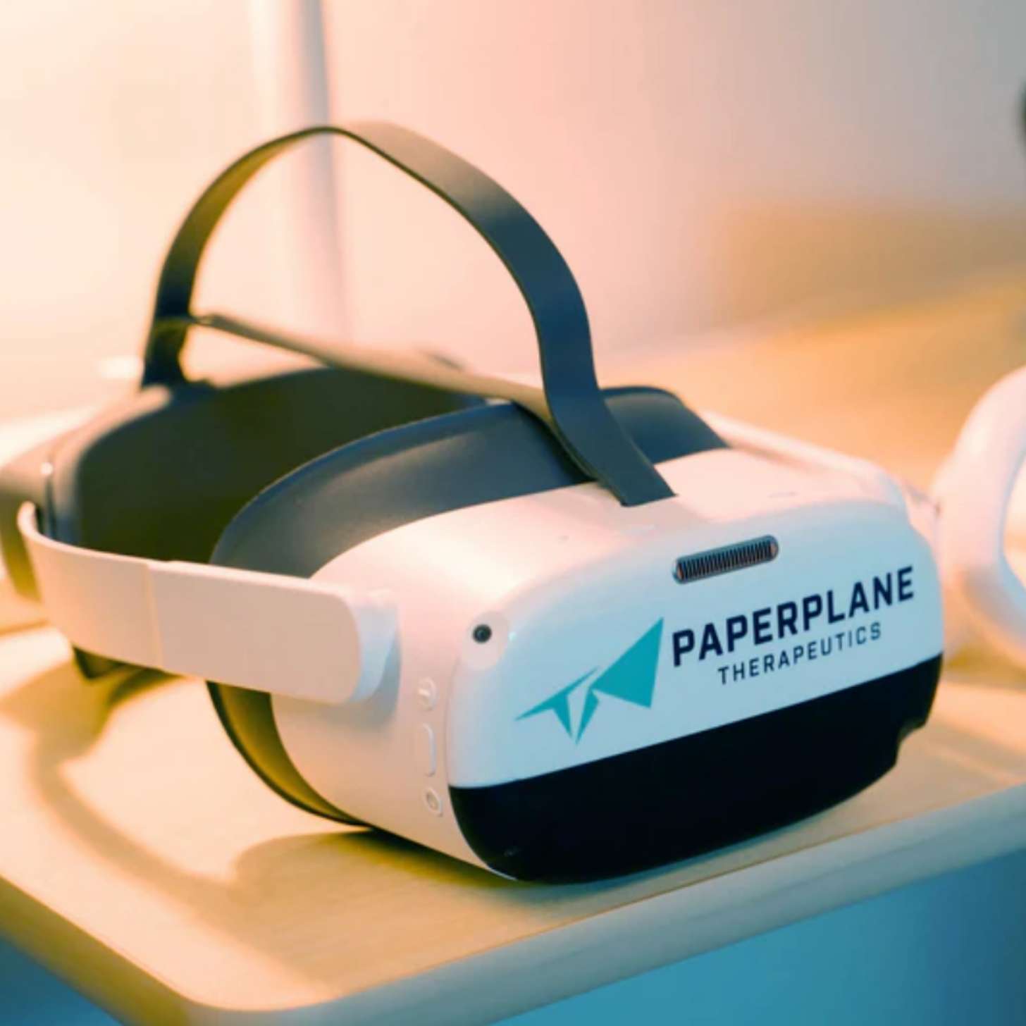 A white VR headset that says Paperplane Therapeutics on the front sits on a table