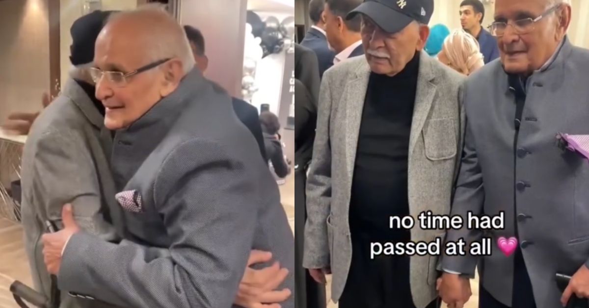 Two elderly men of Indian and Pakistani ethnicity embrace each other, hold hands as they smile