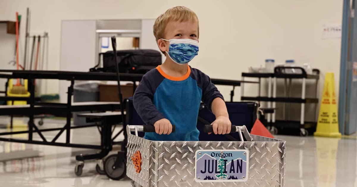6th grader Julian stands behind a metal cart with an Oregon license plate spelling his name